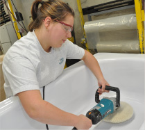 technician polishing the bottom of a bathtub